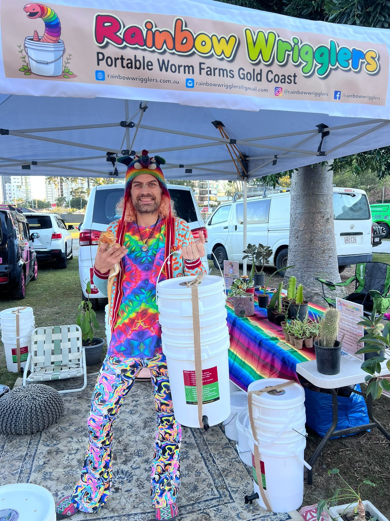 Rainbow standing with a Rainbow Wrigglers worm farm at his Gold Coast market stall